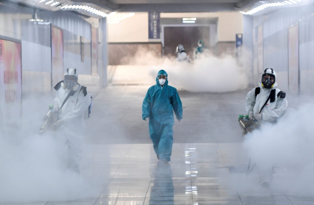Volunteers in protective suits disinfect a railway station as the country is hit by an outbreak of the new coronavirus, in Changsha